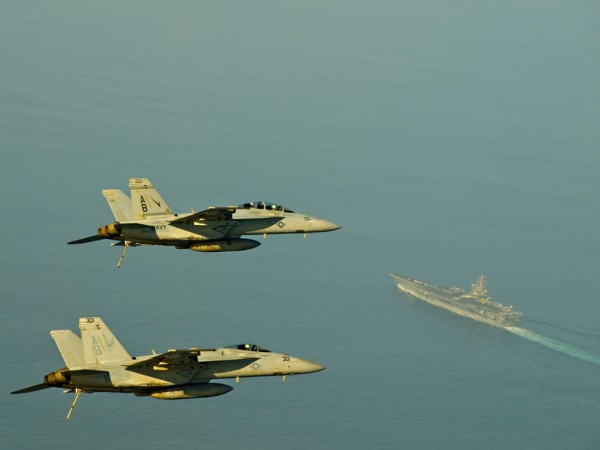 Two FA-18 Super Hornets fly above the aircraft carrier USS Enterprise (CVN 65)