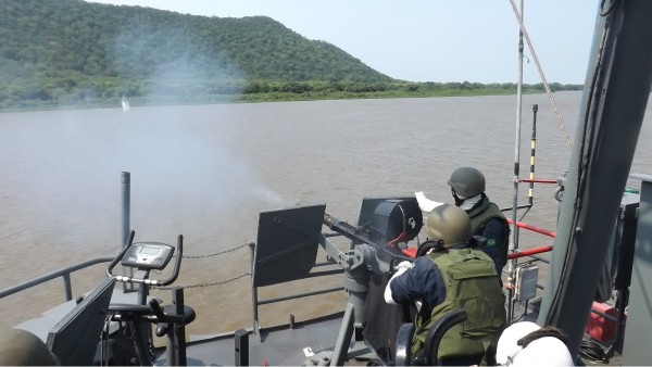 Militar engajando alvo junto a margem com metralhadora MK-4