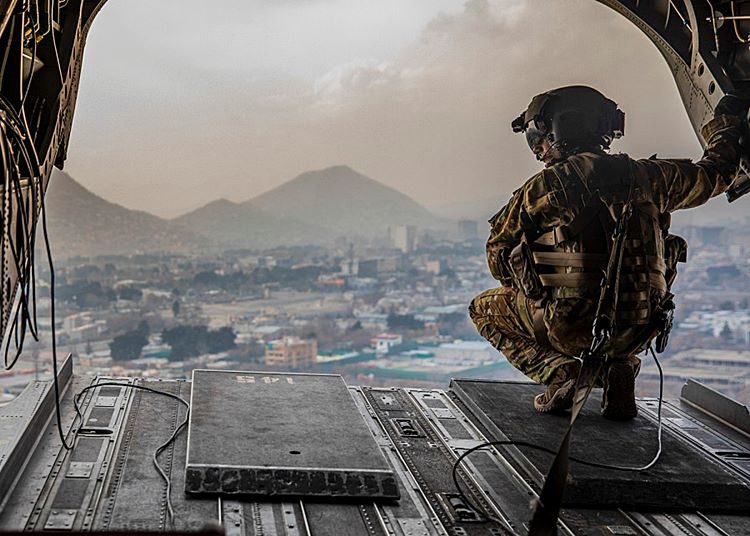 Um soldado dos EUA designado para a 10ª Divisão de Montanha inspeciona a parte traseira de um CH-47 Chinook durante o vôo sobre Cabul, Afeganistão. Foto Jeffery Harris