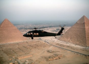 An air-to-air left side view of a UH-60 Black Hawk (Blackhawk) air ambulance helicopter in use during the joint Exercise BRIGHT STAR '83.  The Great Pyramids are visible in the background.