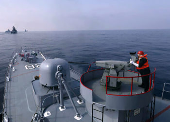 Nesta foto fornecida na sexta-feira, 21 de janeiro de 2022, pelo Exército iraniano, um membro do exército iraniano dispara uma arma durante um exercício naval conjunto do Irã, Rússia e China no Oceano Índico. (Exército iraniano via AP)